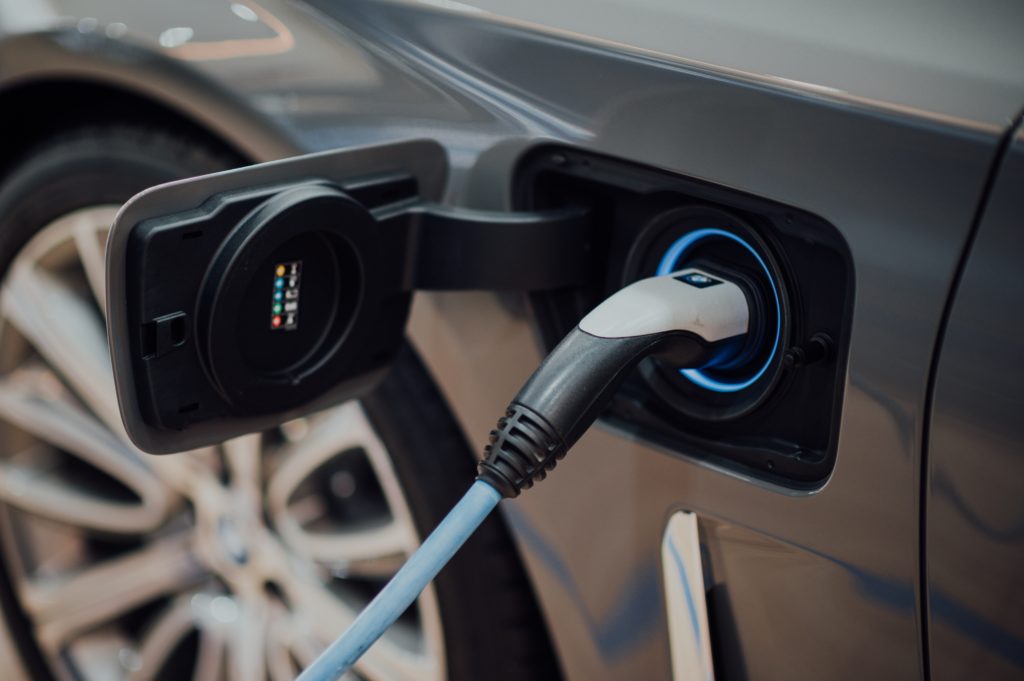 Close up of a brown electric vehicle plugged in to a battery charger